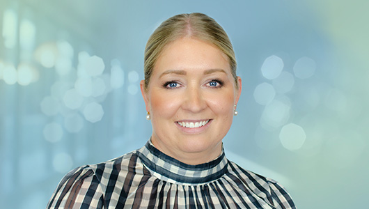 Foto von Verena Prochnow, lächelnd, blonde Haare, karierte Bluse