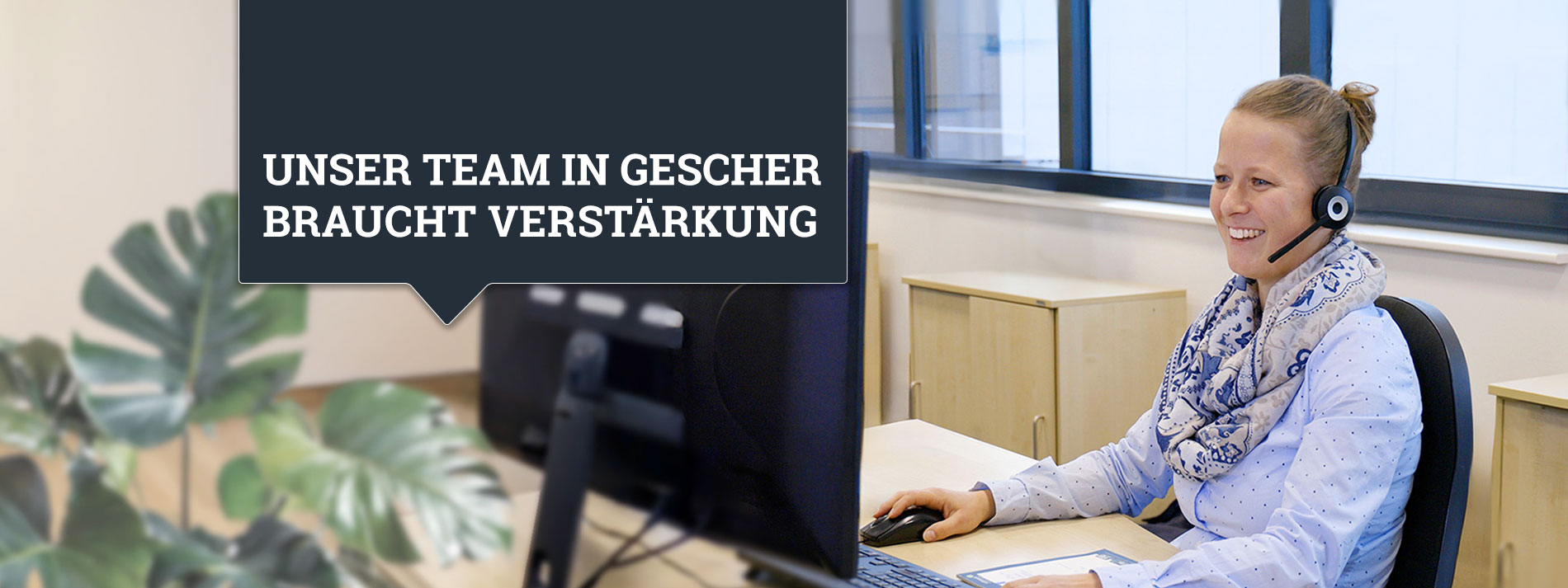 Eine Sachbearbeiterin für Kundenmanagement sitzt während ihrer Arbeit ein einem Schreibtisch und telefoniert mit einem Headset.
