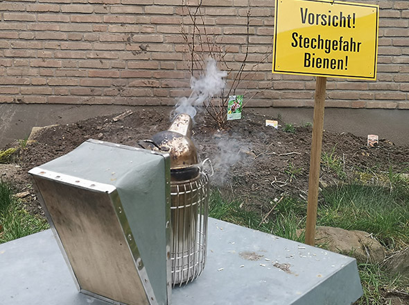 Imker-Rauchkanne und Schild "Vorsicht Stechgefahr Bienen"